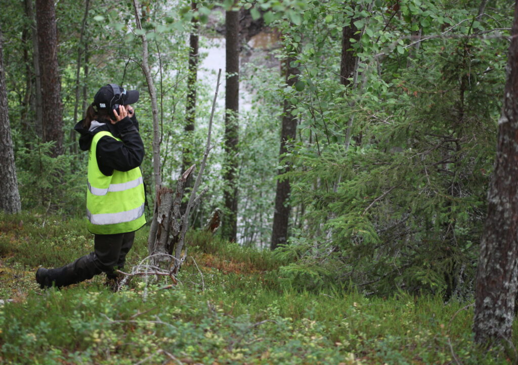 Kvinna med hörselkåpor i skog.